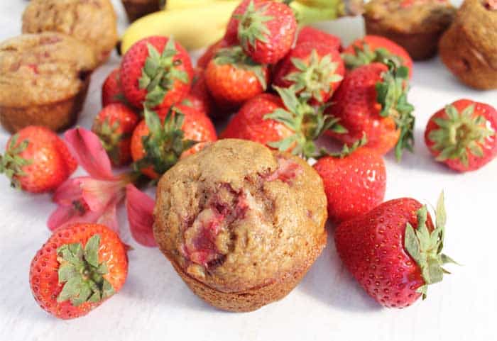 https://2cookinmamas.com/wp-content/uploads/2018/08/Banana-Strawberry-Muffins-single-among-strawberries.jpg