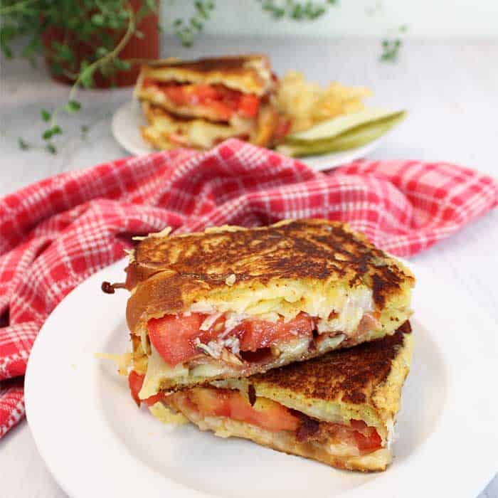 Finished Gourmet Grilled Cheese Sandwich on white plate with another sandwich in background.