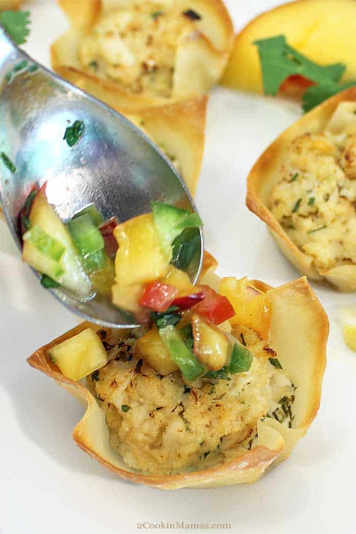 Goat Cheese Crab Wonton Cups with nectarine Salsa adding salsa | 2 Cookin Mamas Goat Cheese Crab Wonton Cups are an easy, tasty appetizer for entertaining. Creamy goat cheese is topped with a mini crab cake and baked in a wonton cup for the perfect handheld appetizer that is sure to please all seafood lovers. Top them with a little nectarine salsa for an extra special kick. #appetizer #crabcakes #goatcheese #fall #recipe #wontoncups #TheFreshMarket TFMCrabBash #AD