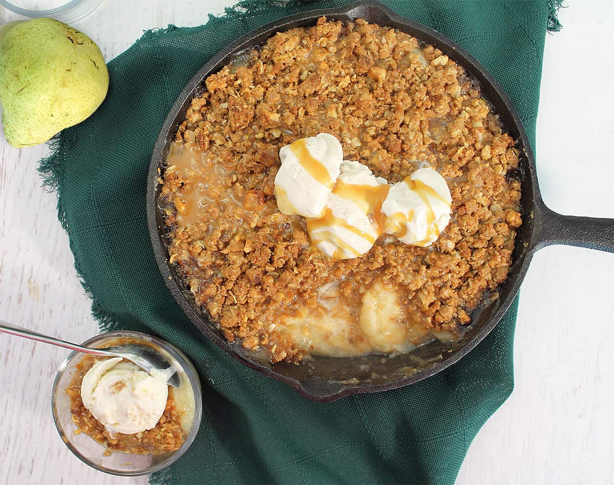 Overhead of pear crumble with oats with ice cream on top.