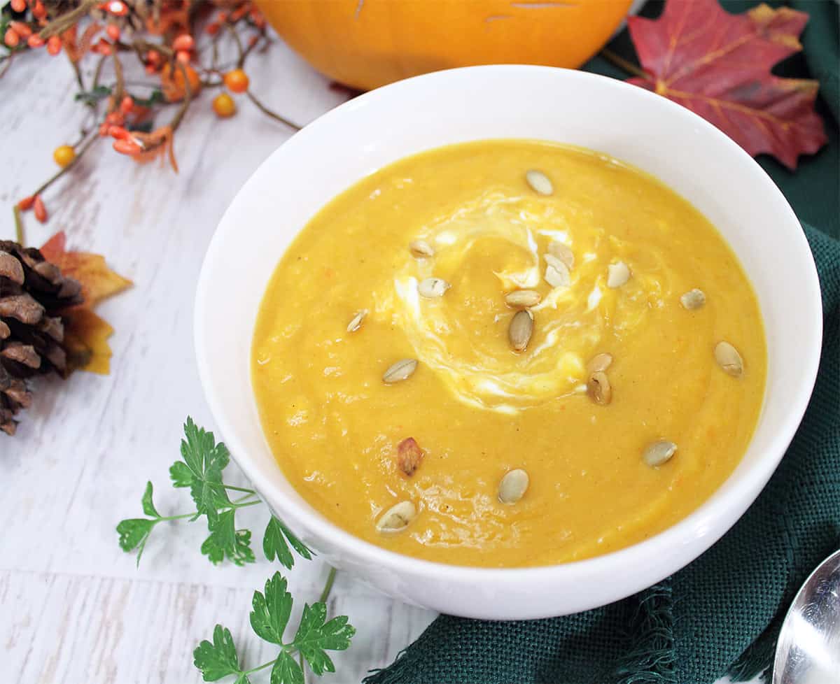 Sweet potato and butternut squash soup in white bowl on green napkin.