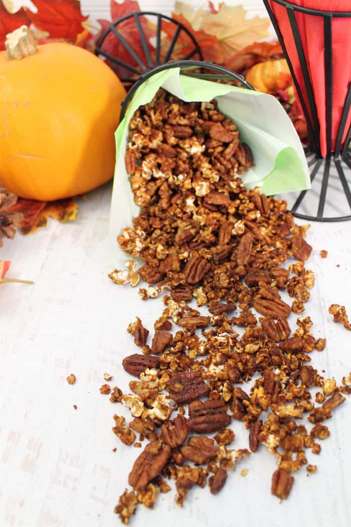 Pumpkin Spice Caramel Corn spilling out of container with pumpkin on side.