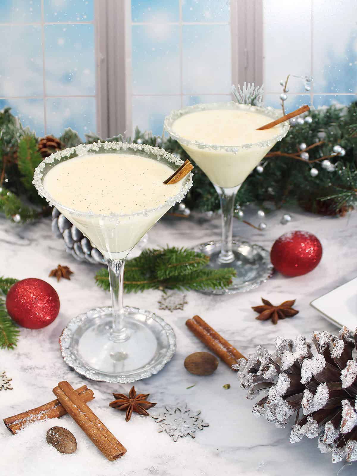 Two eggnog martinis with silver rim and cinnamon stick.