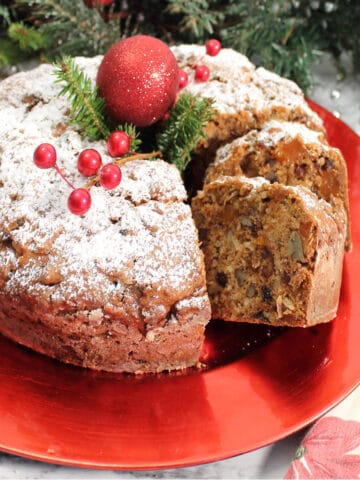 Decorated sliced fruitcake on red platter.