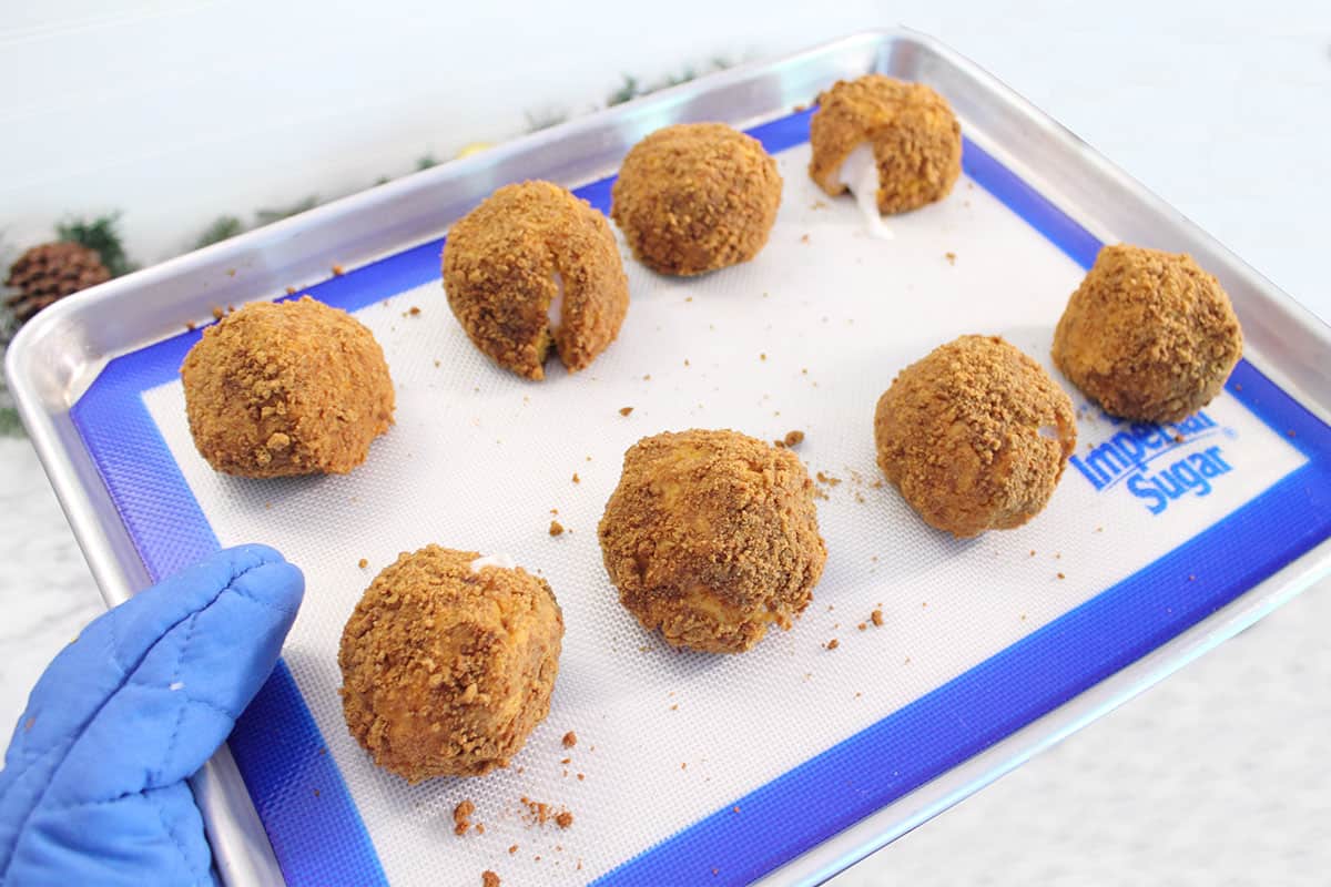 Holding a cookie sheet of baked Sweet Potato Balls right out of oven.