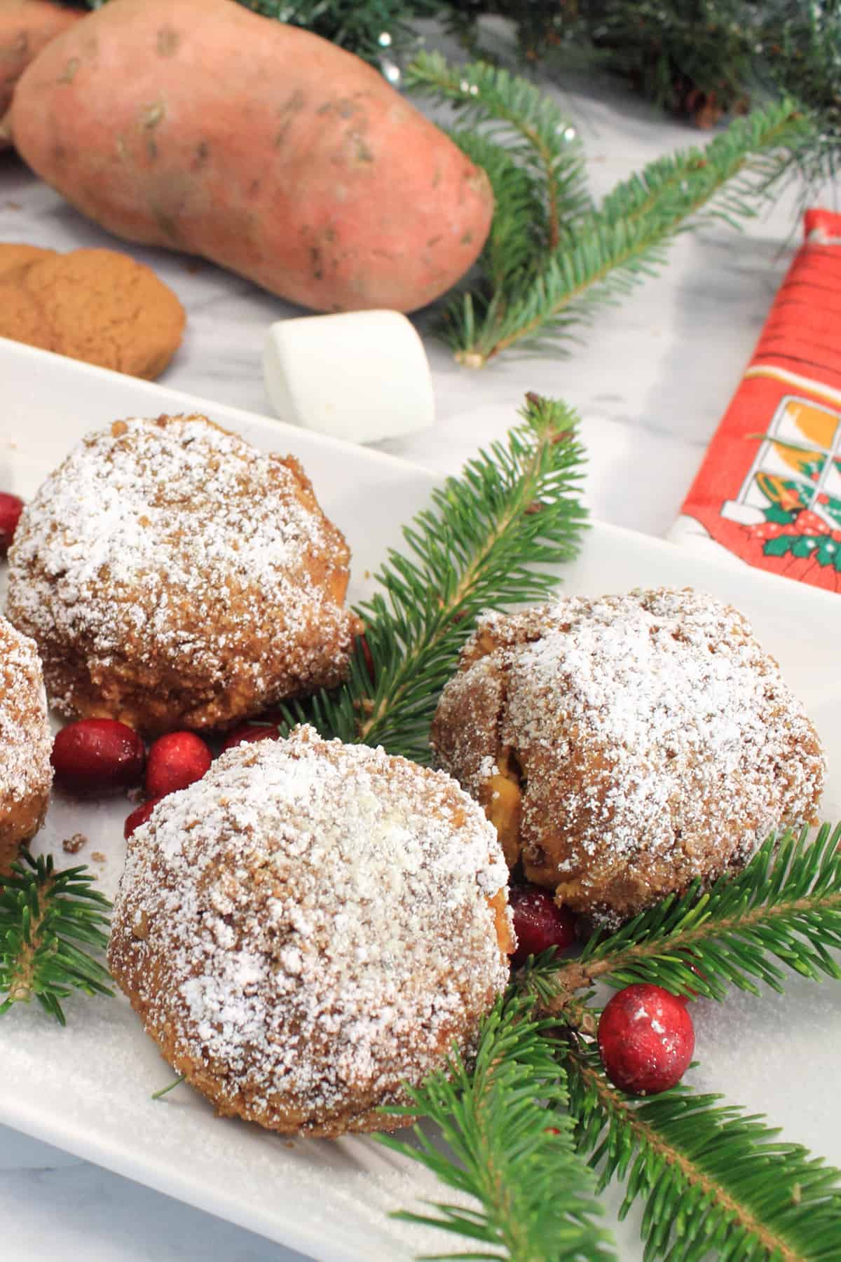 Sweet Potato Puffs on white serving platter with garnishes of cranberries and pine sprigs.