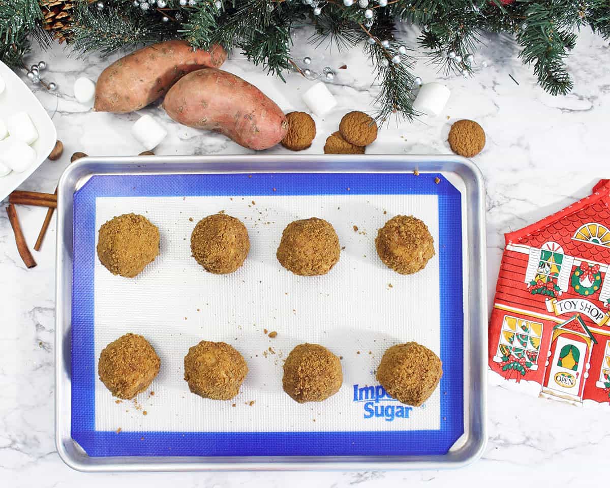 Overhead of Sweet Potato Puffs covered in gingersnap crumbs on a rimmed cookie sheet.