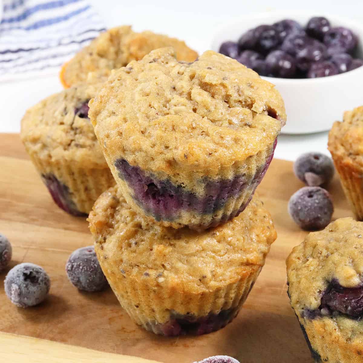 Stacked Blueberry Oatmeal Muffins on wooden board.
