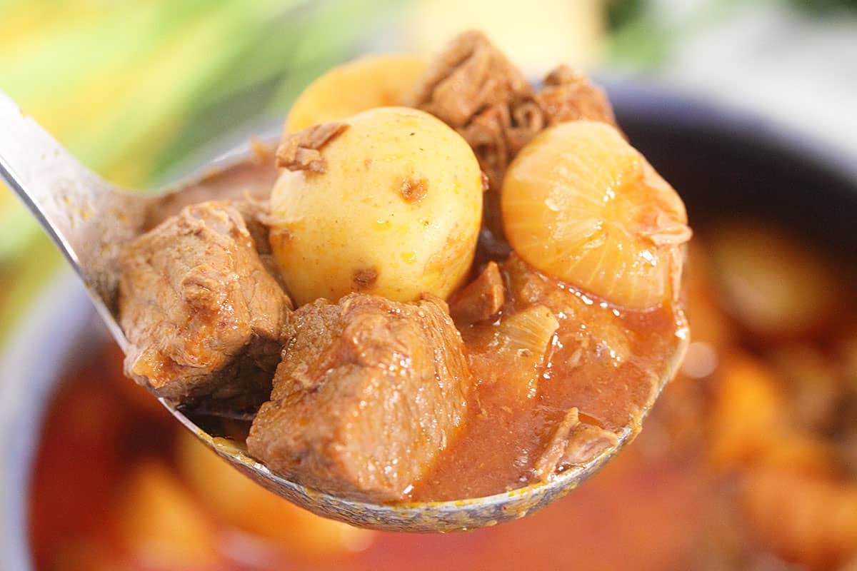 Ladleful of stew above serving bowl.