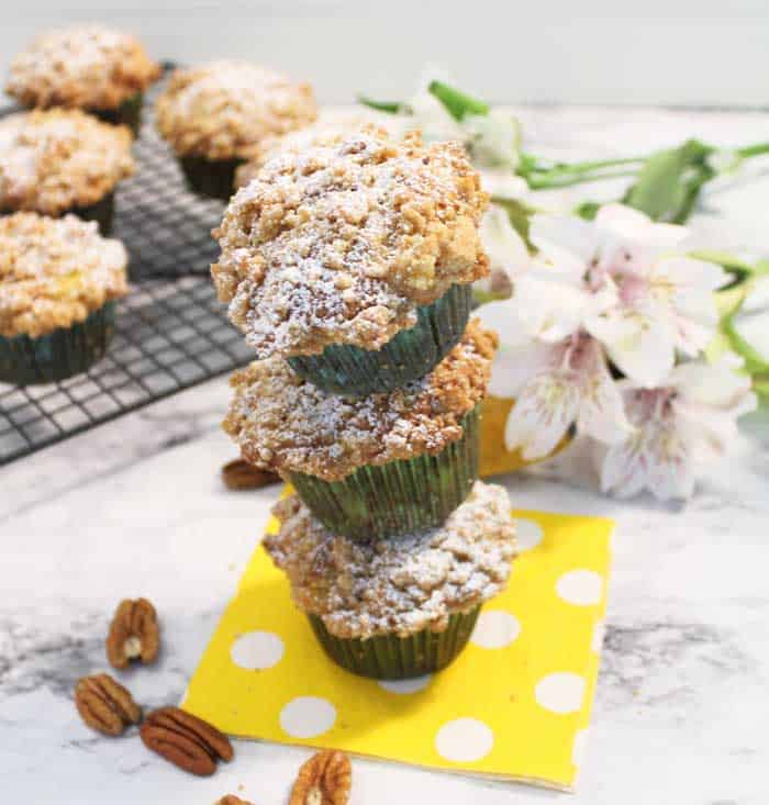 Banana Nut Muffins stacked on yellow polka dotted napkin with flowers in background.
