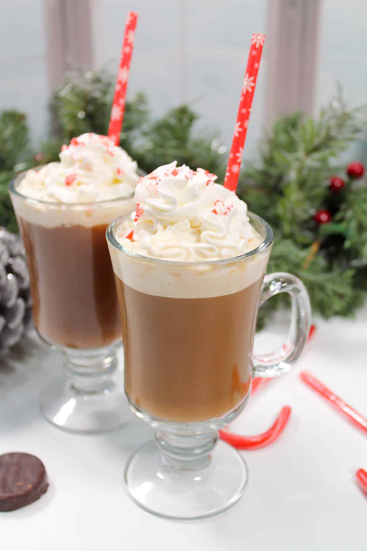 Two peppermint patty coffee cockails with whipped cream and snowflake straws.