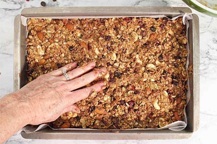 Patting trail mix granola mixture into pan