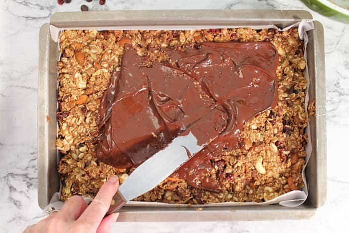 spreading chocolate on granola bars