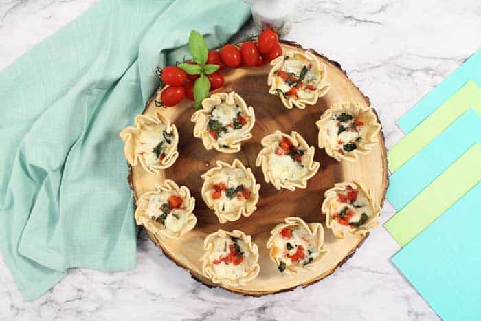 Baked empanadas on wooden board with tomatoes overhead