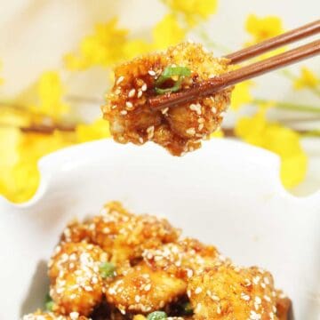 Closeup of crispy chicken in chopsticks.