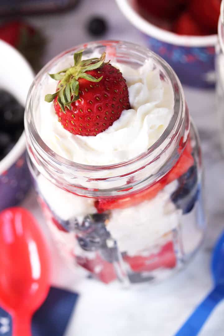 Closeup of red white and blue parfait with strawberry on top.