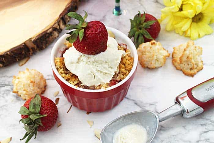 Closeup of crisp in ramekin with ice cream and strawberry on top.