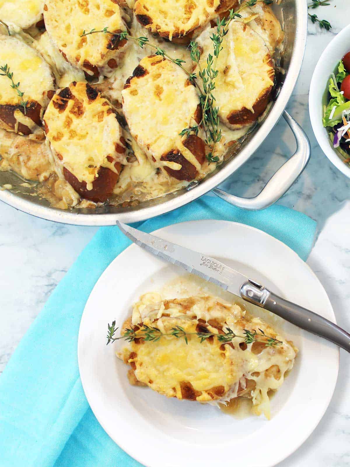 Skillet of French Onion Chicken with plated serving in front.