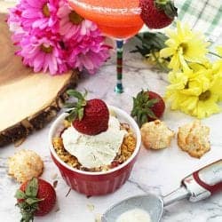 Strawberry Crisp with ice cream on white table with margarita in background.