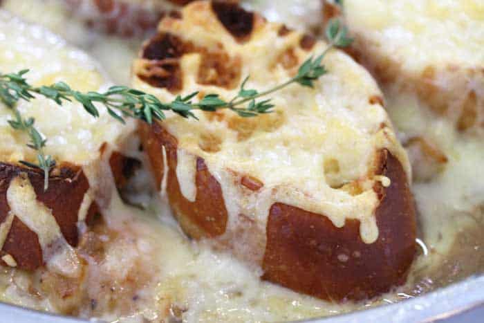 Closeup of cheesy bread with sprig of thyme across top.