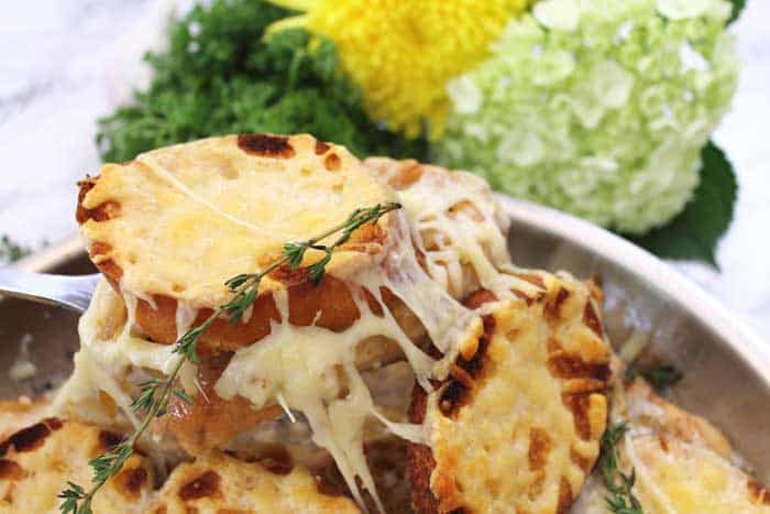 Lifting chicken with cheesy bread out of pan and showing stretchy cheese.