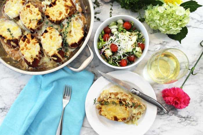 Overhead of French Onion Chicken dinner with salad and wine.