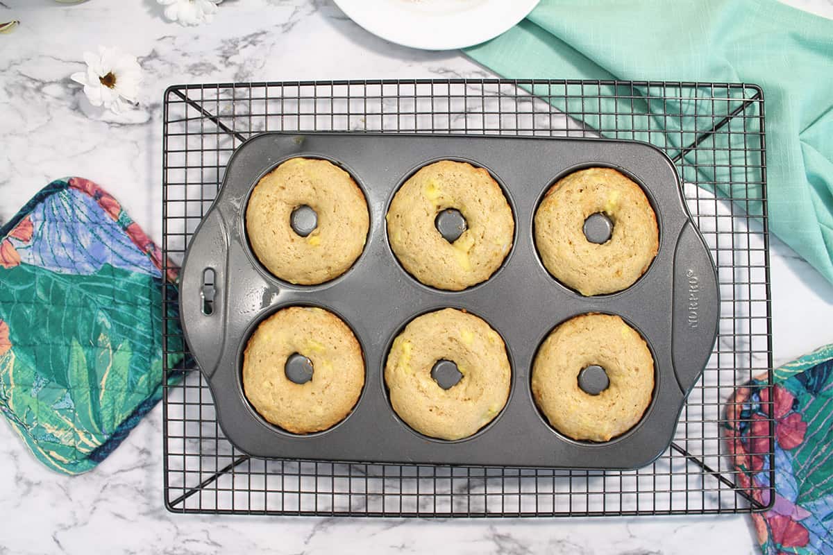 Baked donuts in donut pan on wire rack.