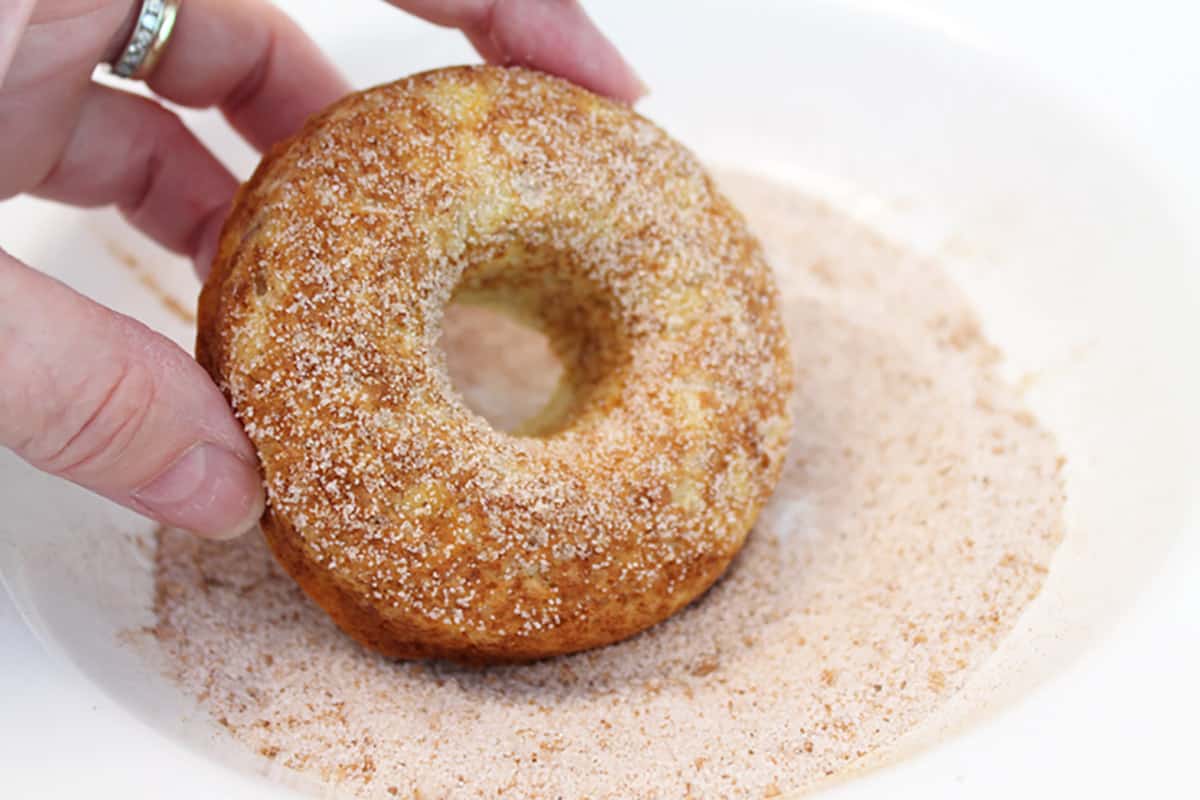 Dipping donut into cinnamon sugar.