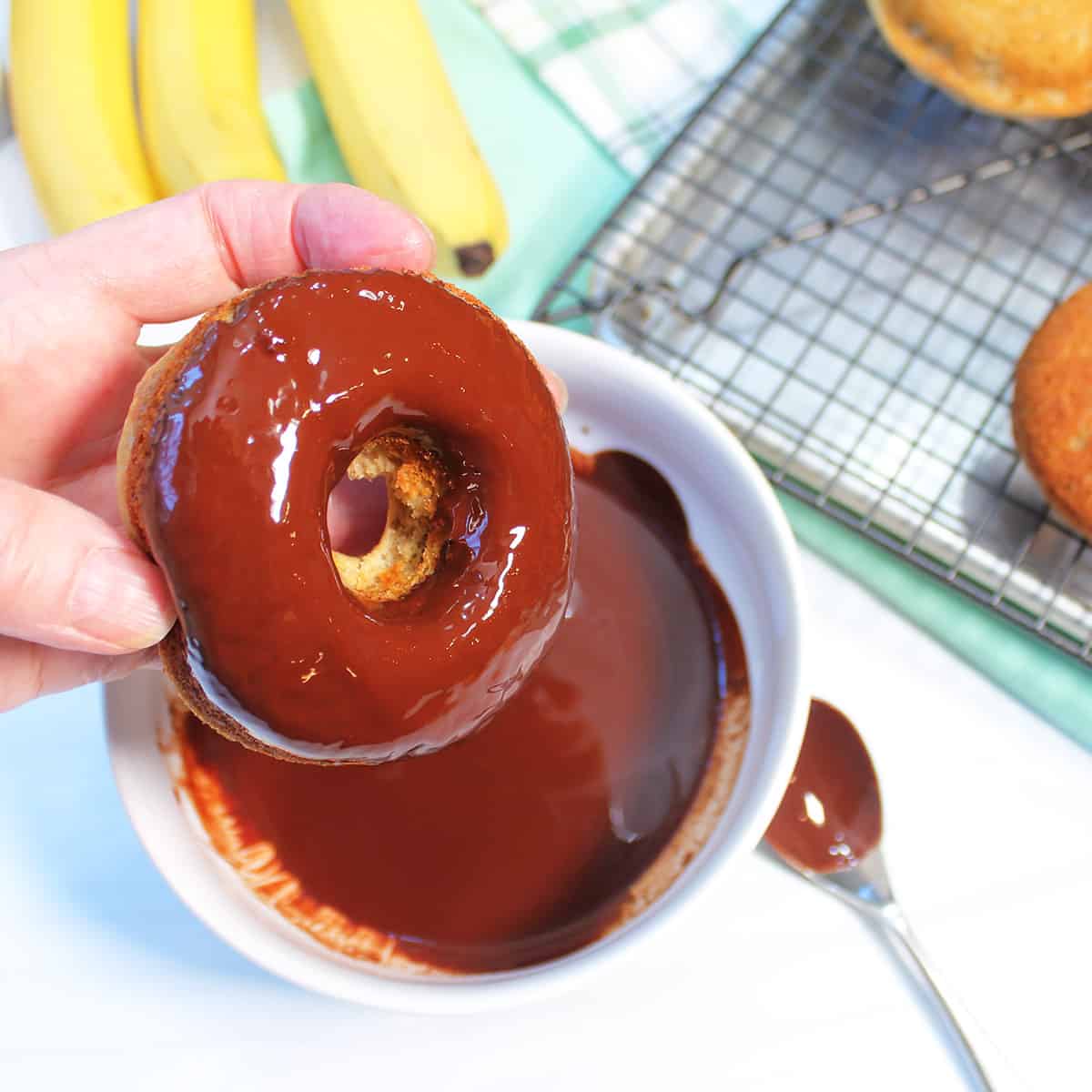 Dipping donut into the melted chocolate.