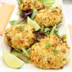 Air fryer tuna patties on platter with greens and lime wedge.