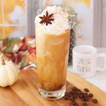Iced Pumpkin Latte on wooden board with coffee beans.