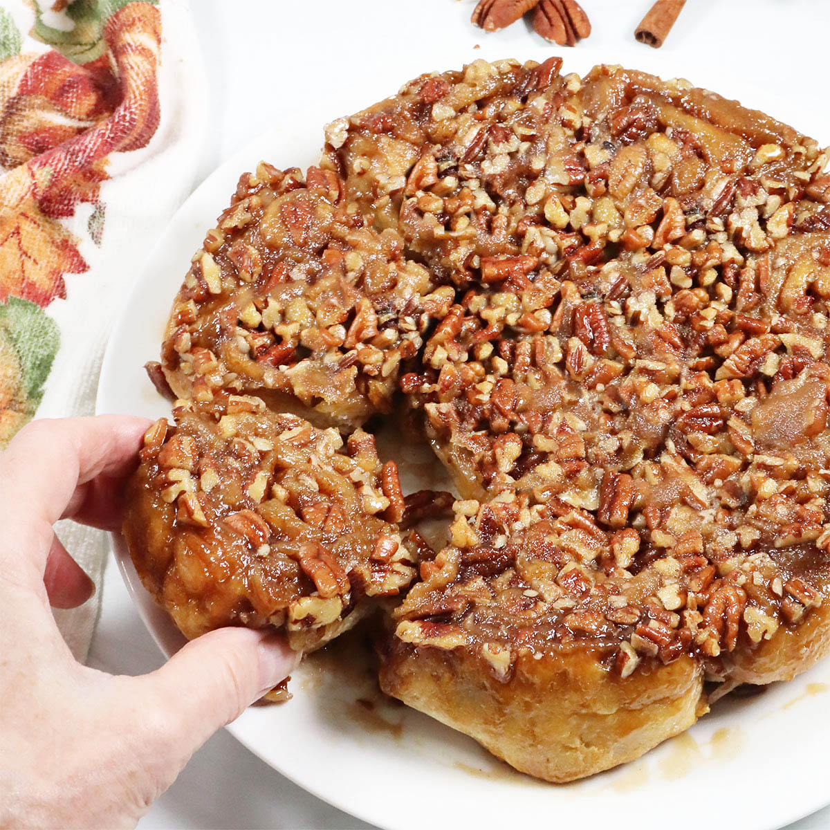 Grabbing a maple pecan sticky bun from plate.