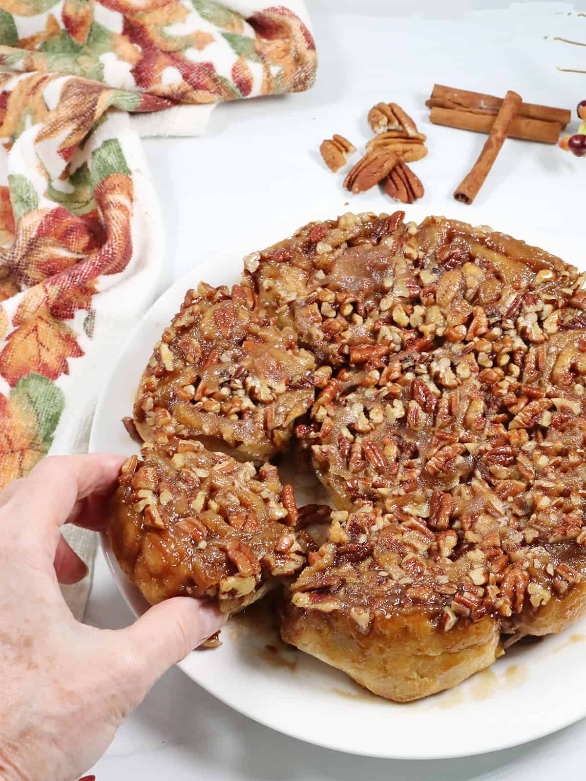 Grabbing a Maple Pecan Sticky Bun from plate.