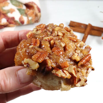 Holding sticky bun showing caramel topping.