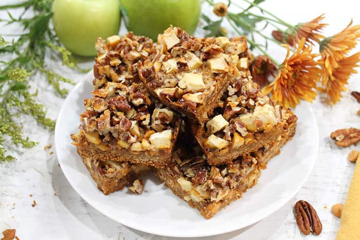 Plated Cinnamon Apple Hello Dolly Bars on white plate with flowers and apples.