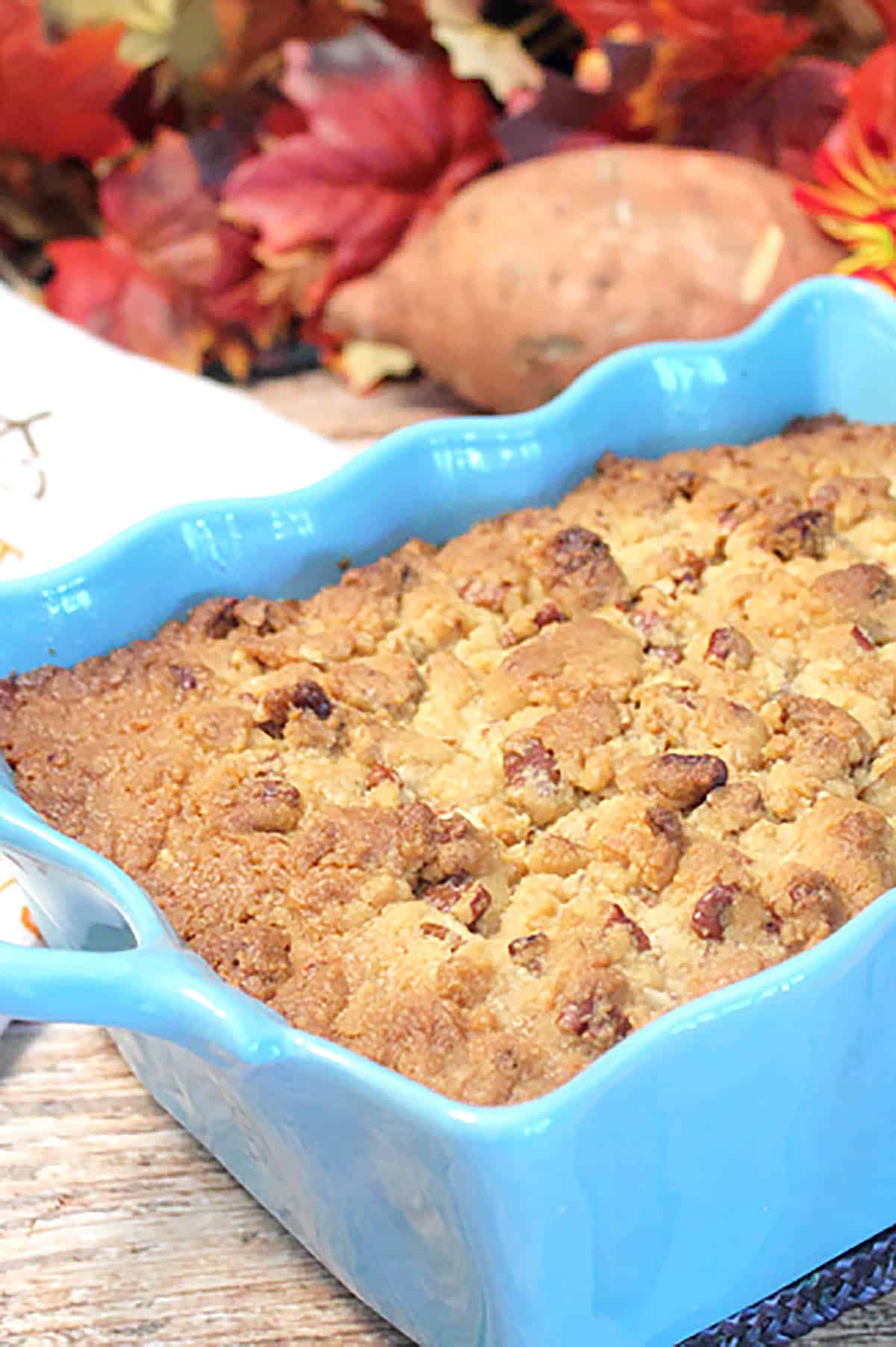 Showing corner of casserole with streusel up close with fall leaves.