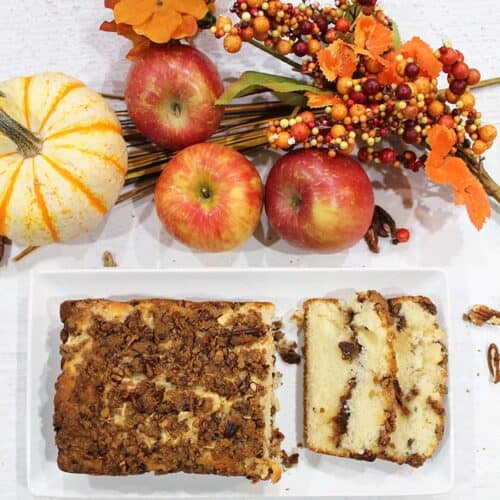 Overhead of sliced apple bread on white plate with fall fruits.