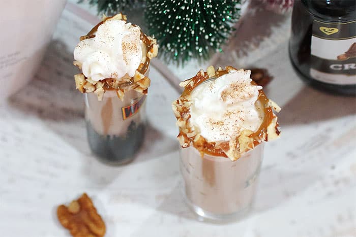 Overhead shot of martini shot with rim coated in caramel and chopped nuts and a swirl of whipped cream.