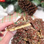 Holding a piece of s'mores graham cracker toffee over plateful of Christmas crack.
