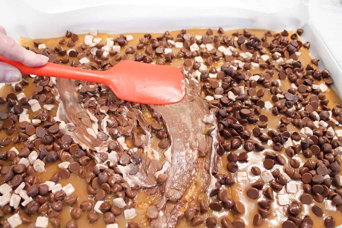 Smoothing chocolate chips and marshmallows with silicone spatula.