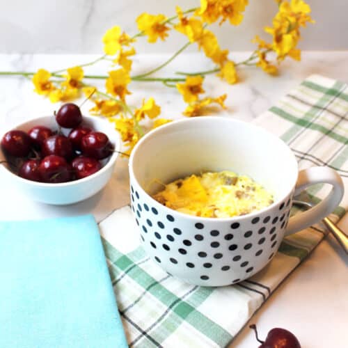 Baked sausage scramble in white polka dot mugs with cherries and yellow flowers.