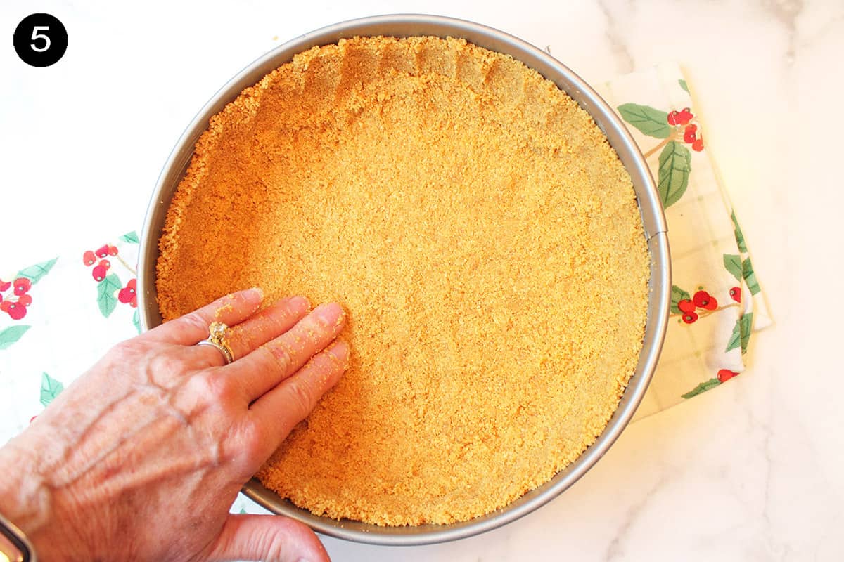 Patting graham cracker mixture into pan.