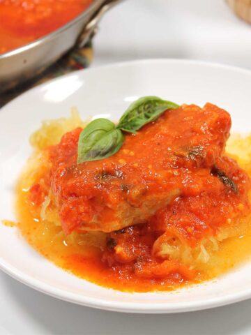 Closeup of Italian pork chop on top of spaghetti squash.