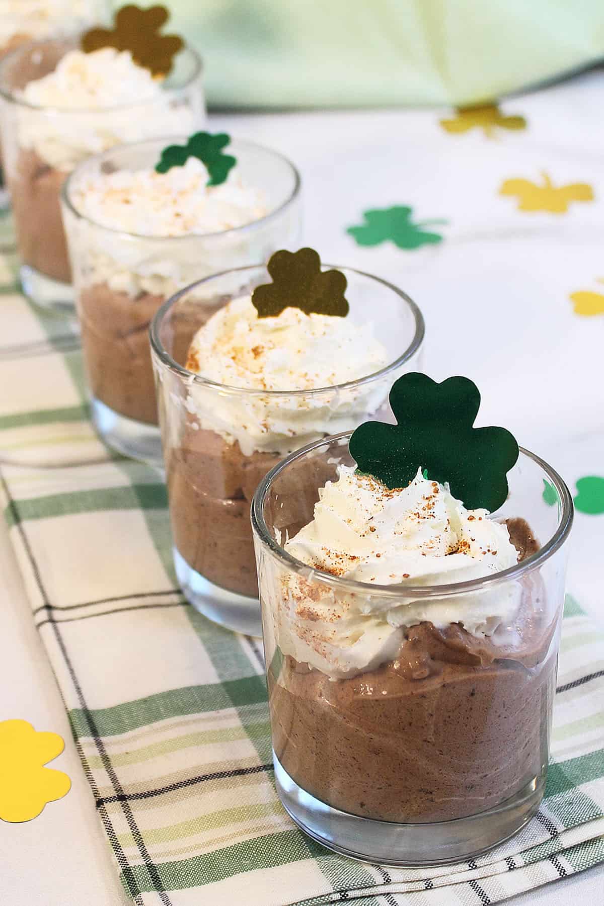 Mousse filled small jars lined up on green checkered towel.