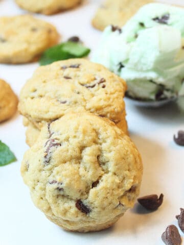 Stack of cookies with other cookies and chips scattered around with scoop of ice cream.