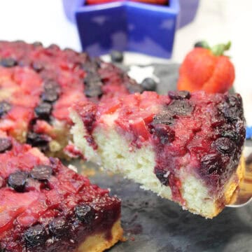 Lifting slice of cake with berry topping.