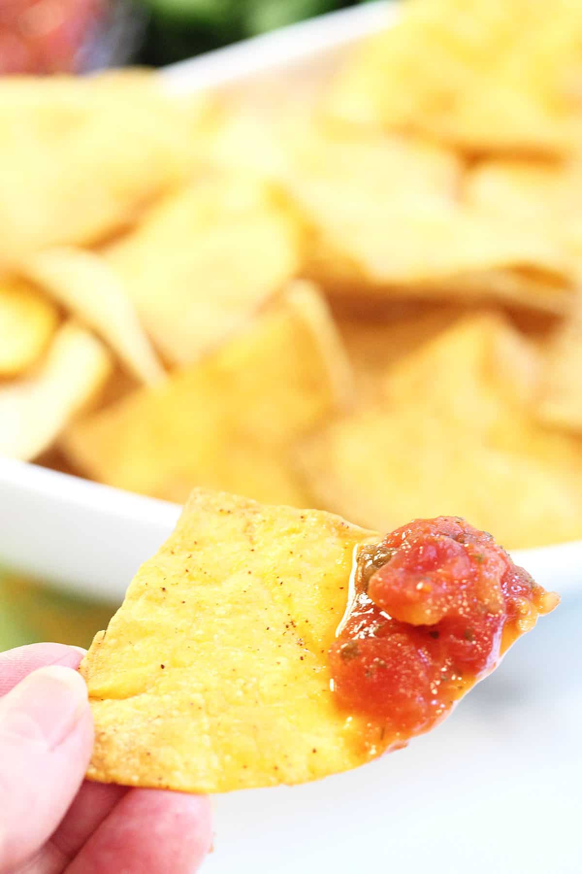 Closeup holding a crispy chip with salsa on it.