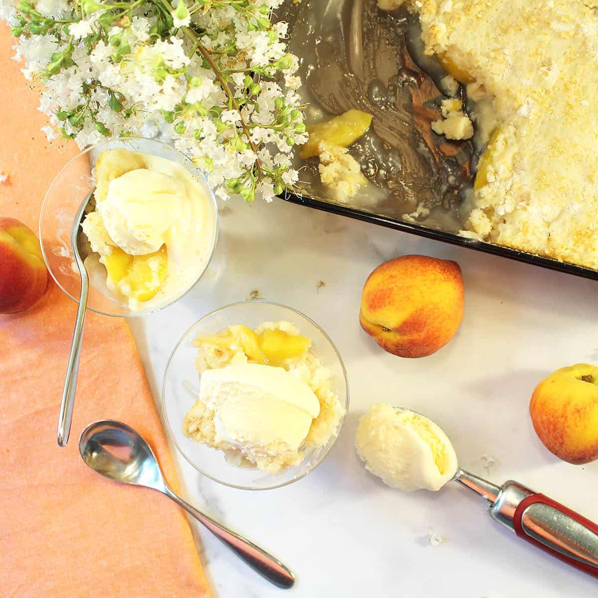 Overhead of 2 servings next to peach napkin with peaches and scoop of ice cream next to it.