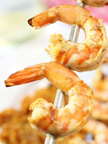 Closeup of 2 skewered shrimp over plated dinner.