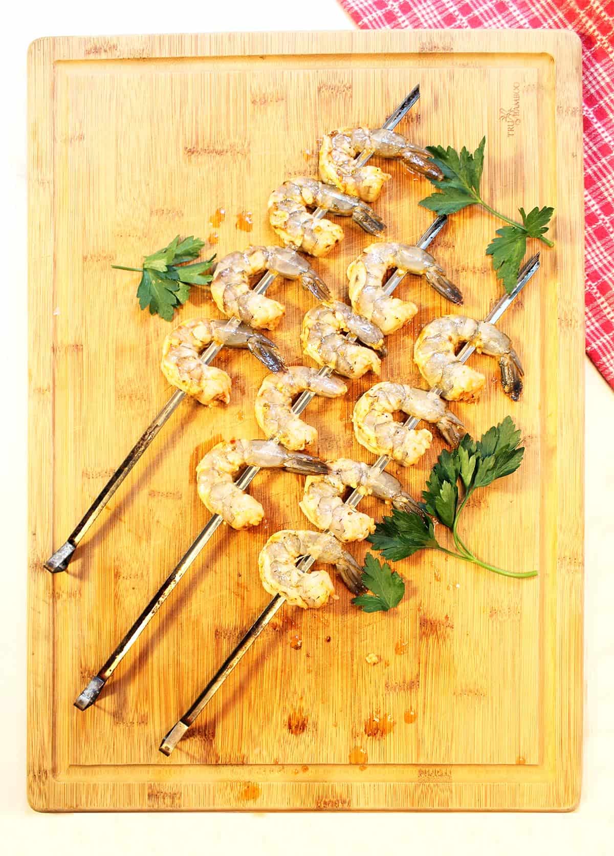 Skewer the marinated shrimp shown on wooden board.